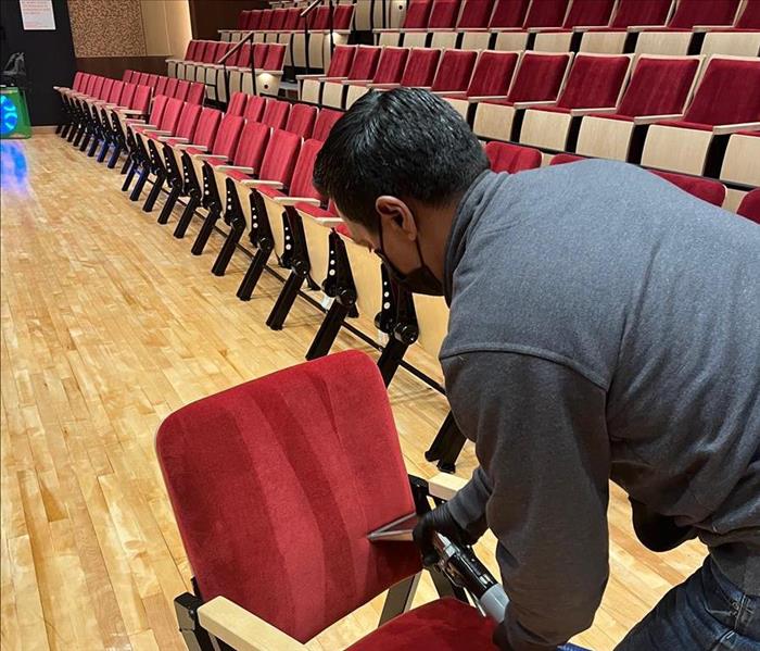 A SERVPRO Employee is cleaning auditorium chairs after a fire.